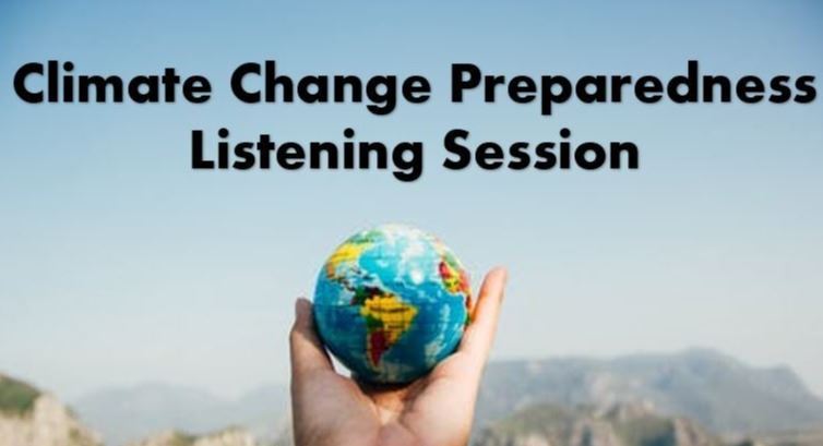 A small globe of earth held in a person's hand in front of a mountain landscape 