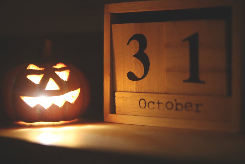 A jack-o-lantern sits to the left of wooden numbers 3 and 1