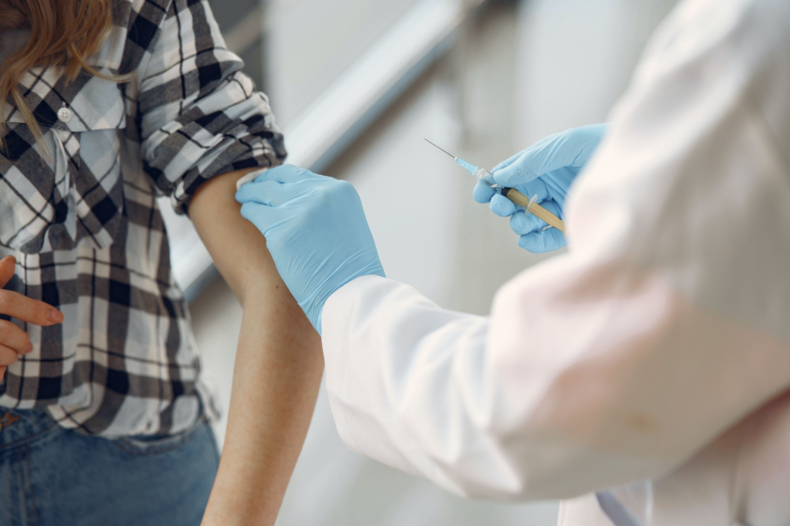 A person in a lab coat administers a vaccine to someone